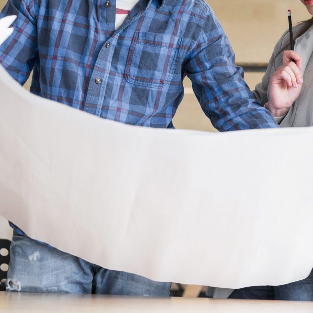 beautiful-businesswoman-looking-blue-print-hold-by-her-male-colleague